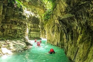 Visitors swimming through a turquoise canyon at Damajagua Waterfalls